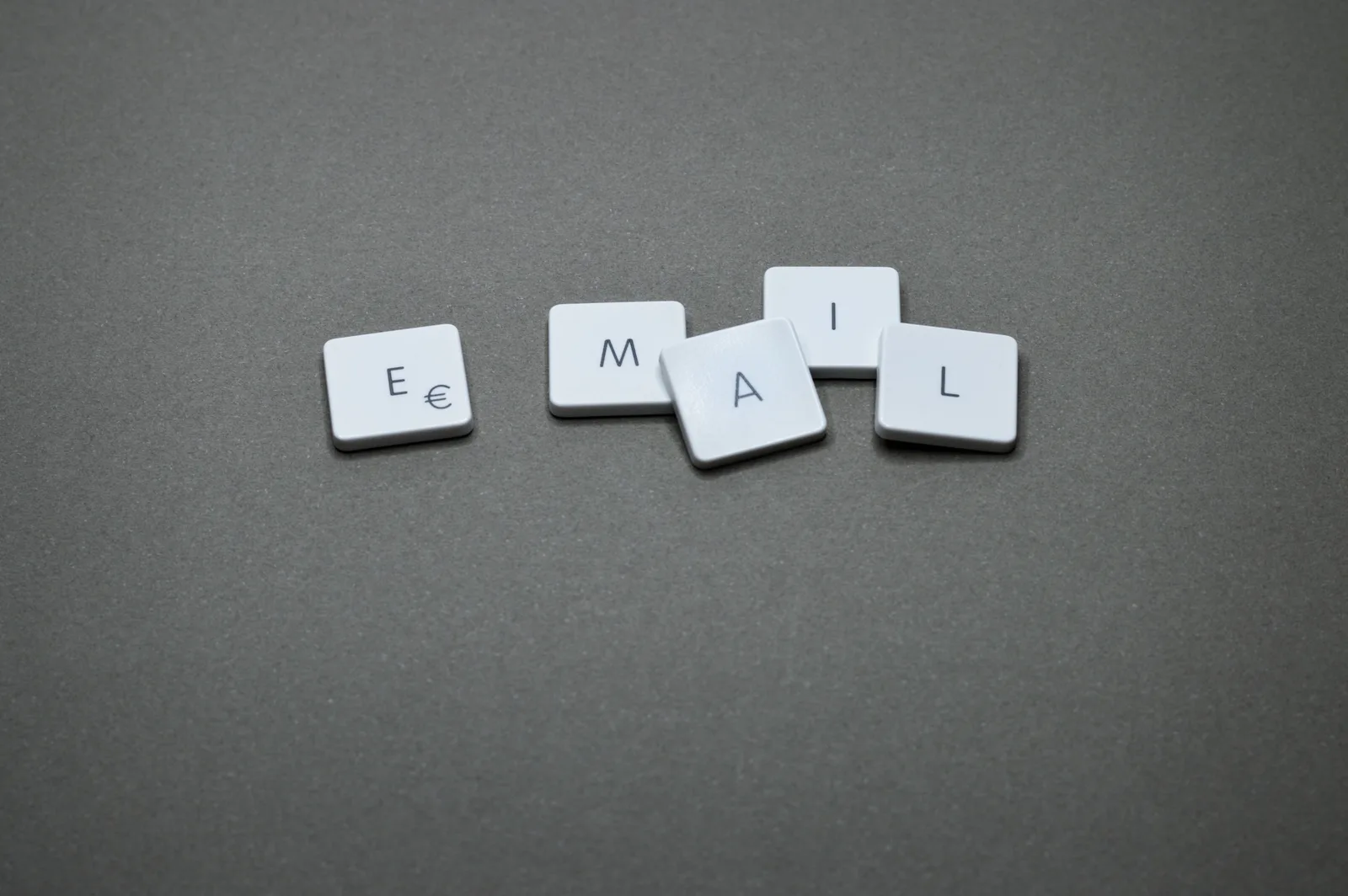 Close-up of the word 'email' formed with letter tiles on a gray surface. How to improve startup email marketing: audit, authenticate, measure