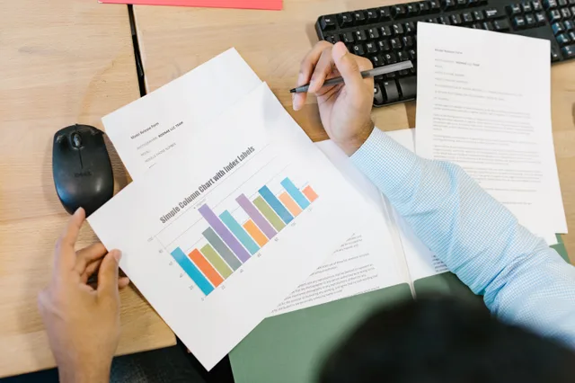 A business analyst reviews a colorful bar chart and documents at a desk, indicating data analysis. Best startup market research tools: a ranked shortlist with reasons