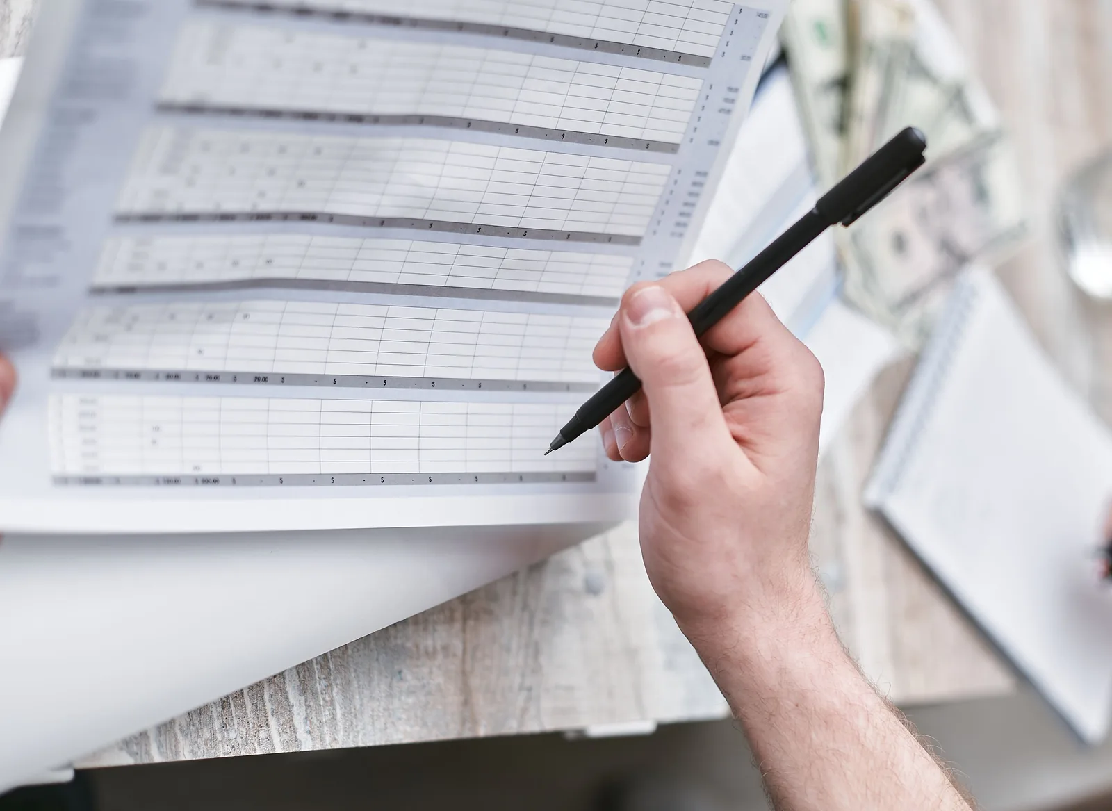A close-up of a person holding a pen reviewing a financial document with cash visible, ideal for business themes. Attribution is not incremental lift: startup paid acquisition mistakes