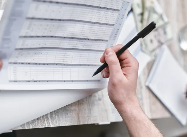 A close-up of a person holding a pen reviewing a financial document with cash visible, ideal for business themes. Attribution is not incremental lift: startup paid acquisition mistakes