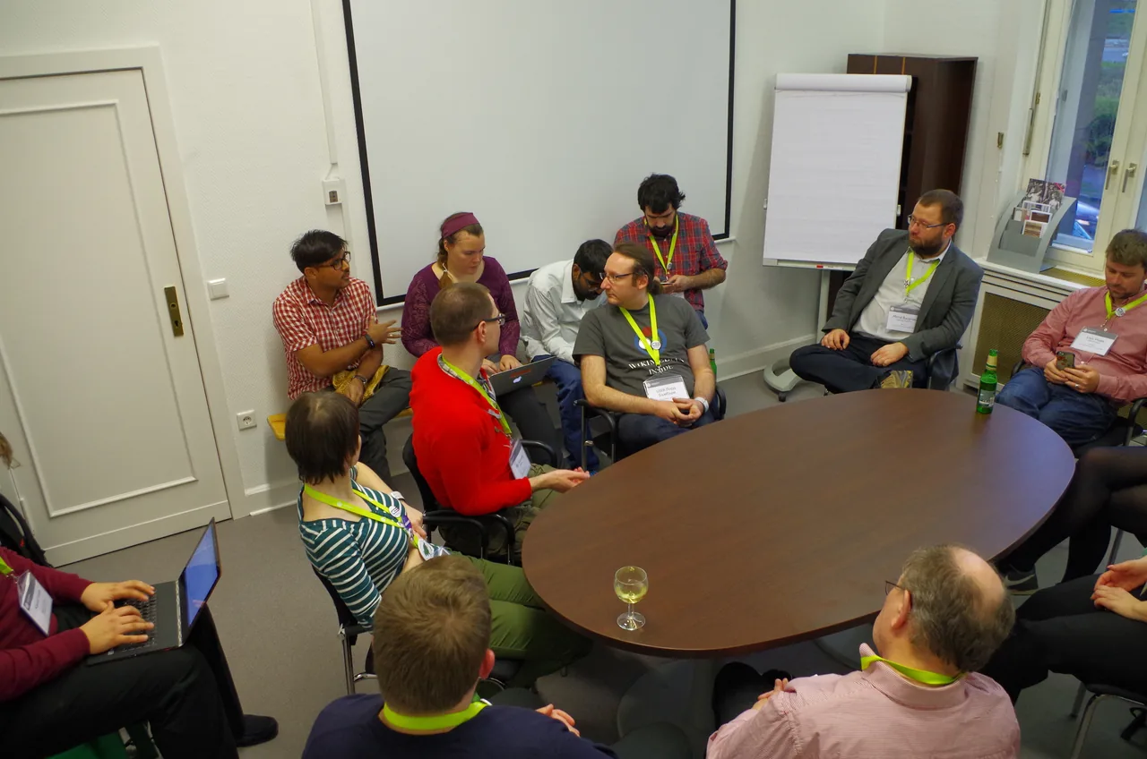 Conference participants discuss ideas around an oval table during a collaborative meeting.